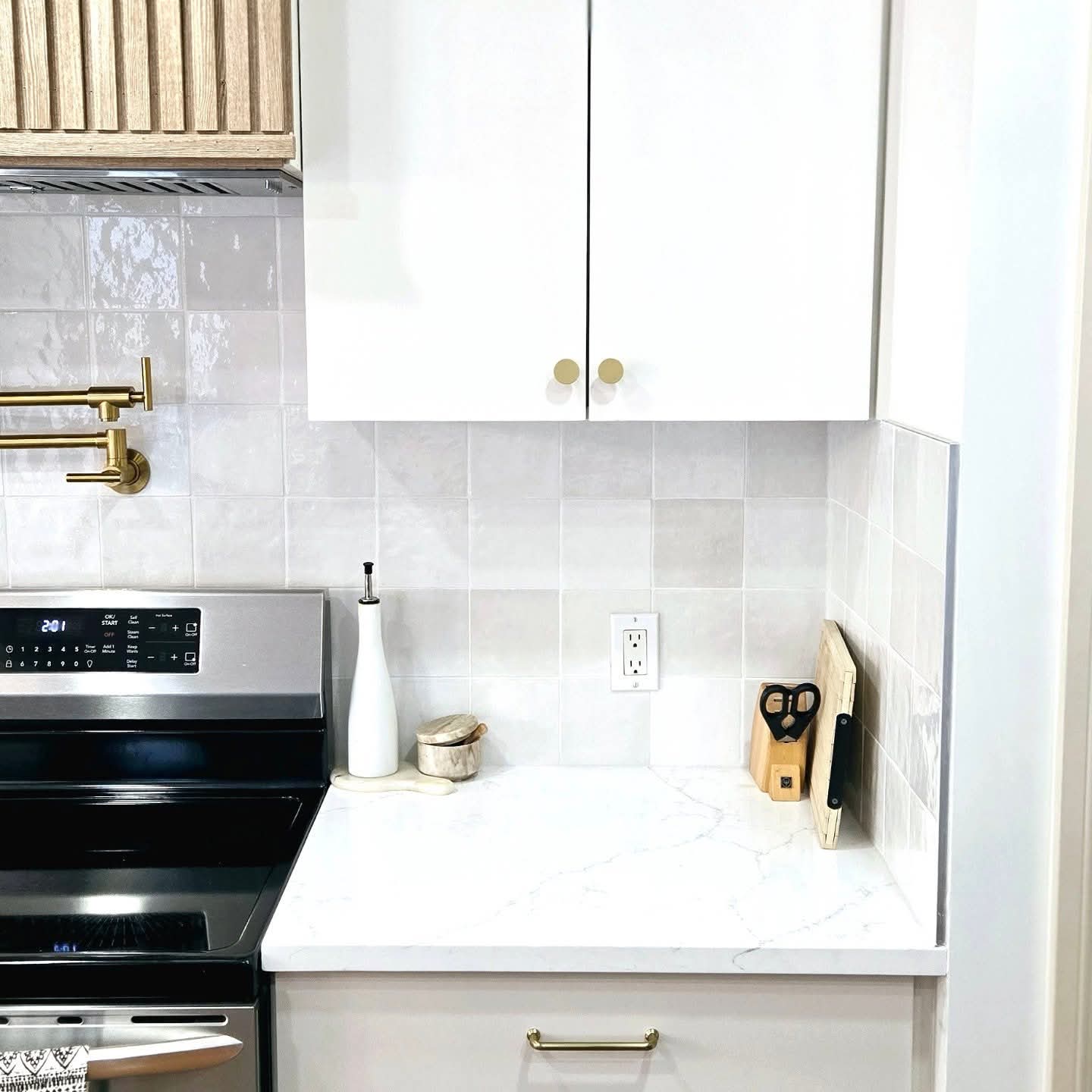 Cabinet refinishing services in Calgary by Lady J's Painting & Decorating Sprayed white kitchen upper cabinets with brass hardware and tile backsplash refinished by Lady J's in Marda Loop, Calgary
